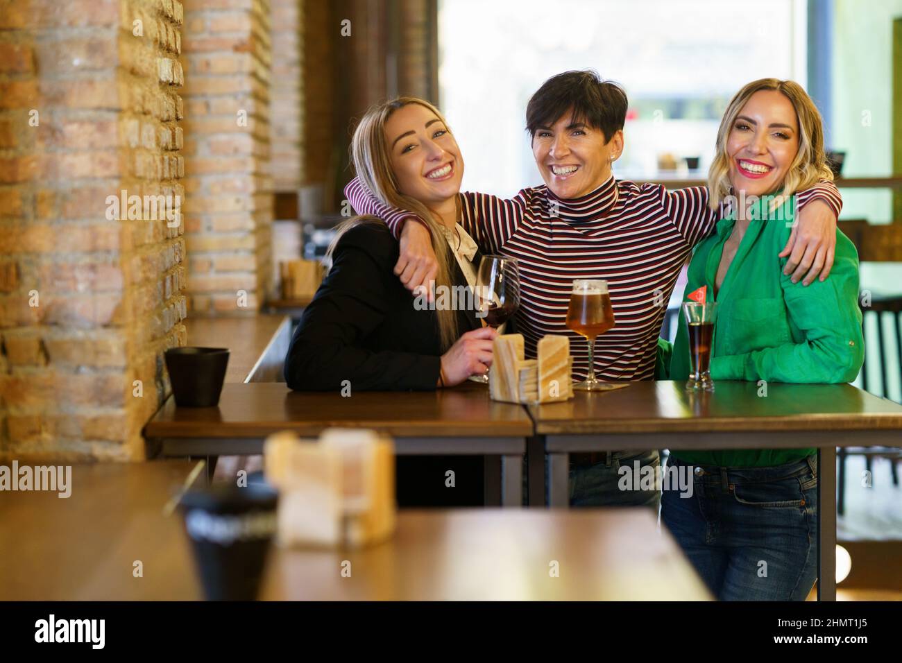 Fröhliche Freundinnen umarmen sich während der Party in der Bar Stockfoto