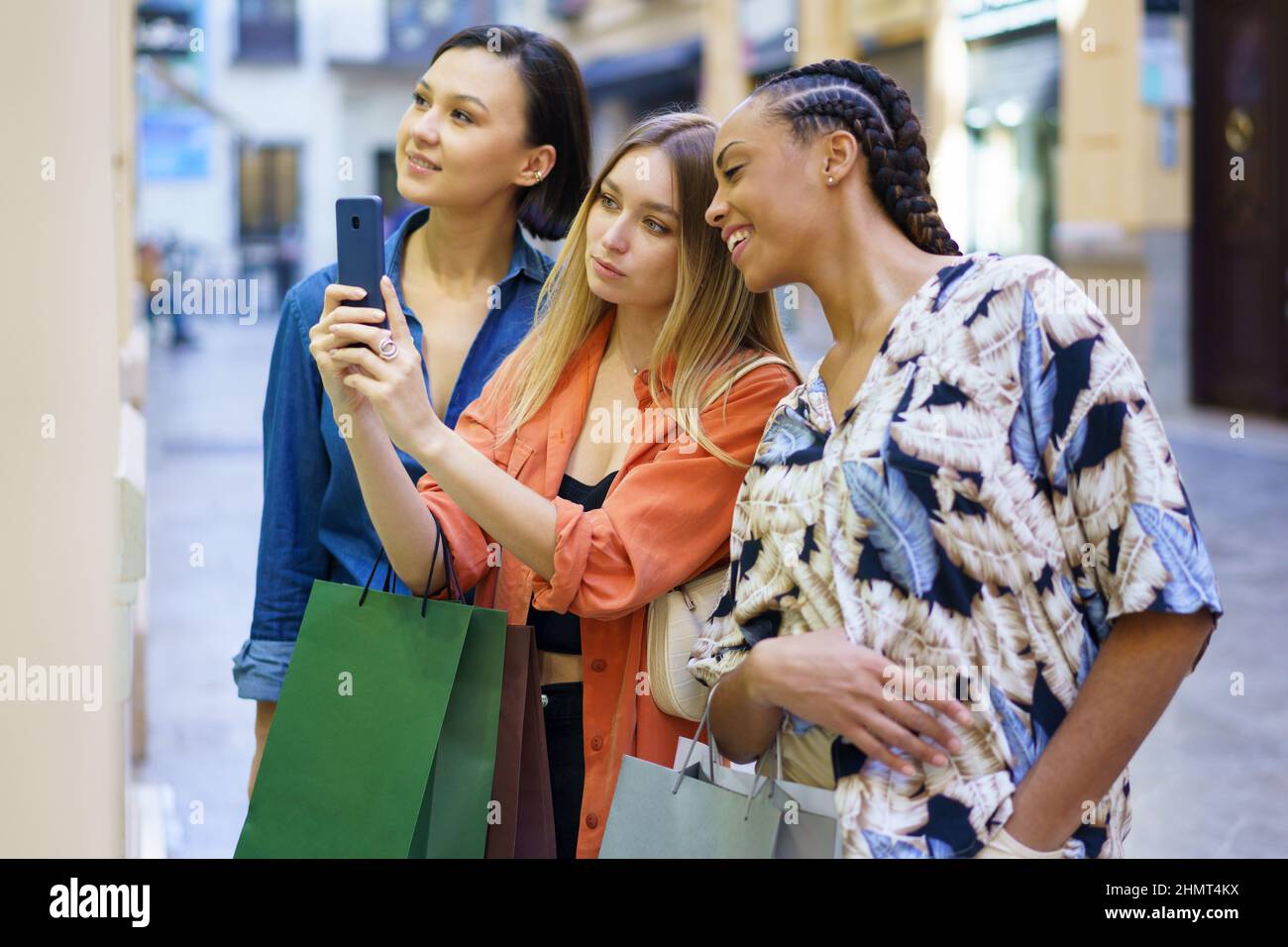 Multiethnische Frauen, die bei der Auswahl von Waren ein Foto von einer Vitrine machen Stockfoto