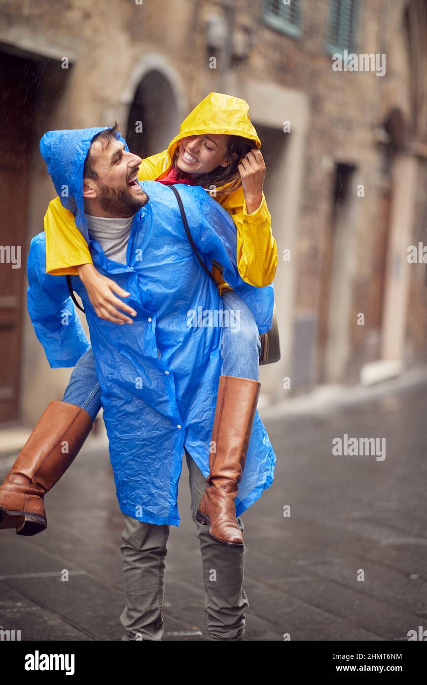 Ein junges verliebtes Paar hat Spaß, während es an einem regnerischen Tag entspannt durch die Stadt geht. Gehen, Regen, Stadt, Beziehung Stockfoto