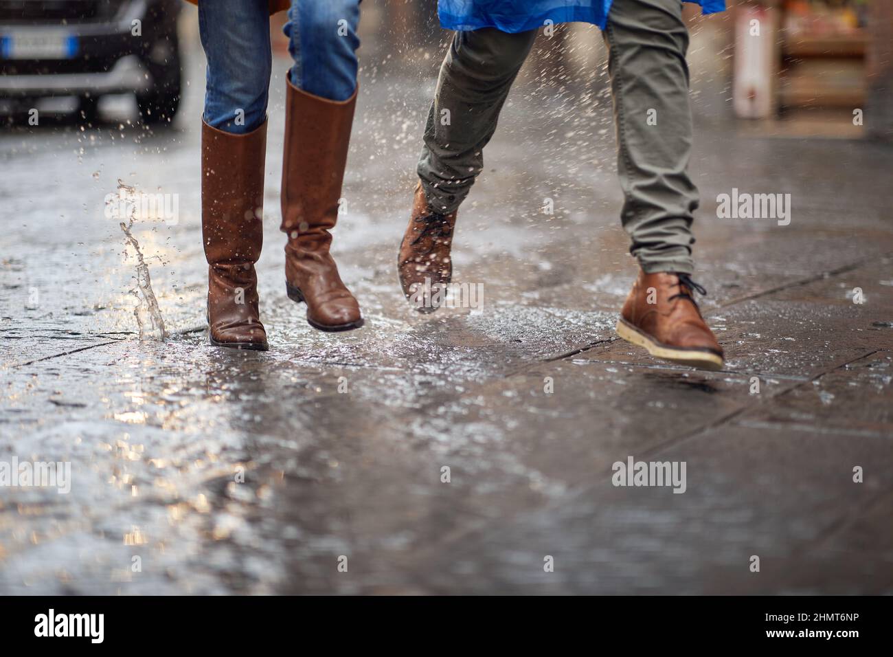 Nahaufnahme der Beine eines jungen Paares, das eilig auf dem Regen in der Stadt herumläuft. Gehen, Regen, Stadt, Beziehung Stockfoto