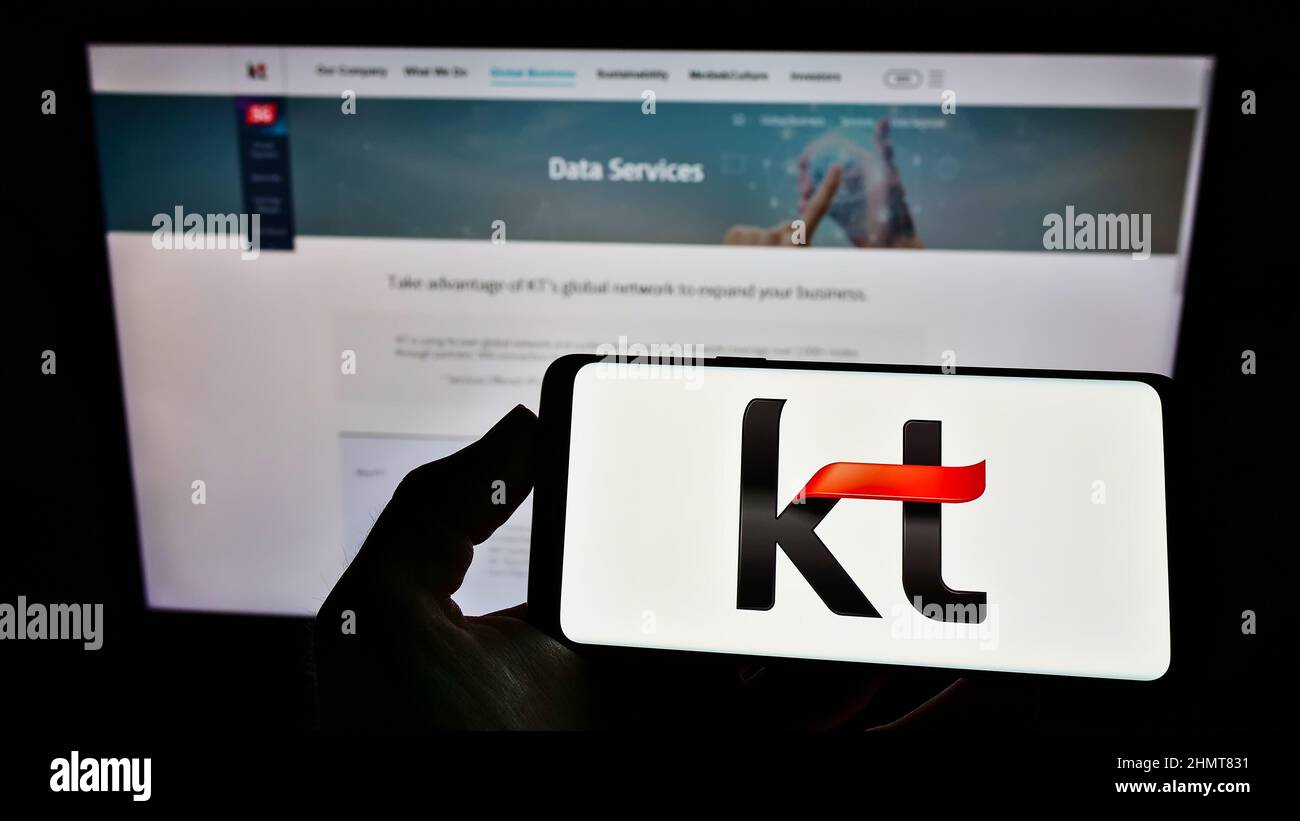 Person, die das Smartphone mit dem Logo des Telekommunikationsunternehmens KT Corporation auf dem Bildschirm vor der Website hält. Konzentrieren Sie sich auf die Telefonanzeige. Stockfoto