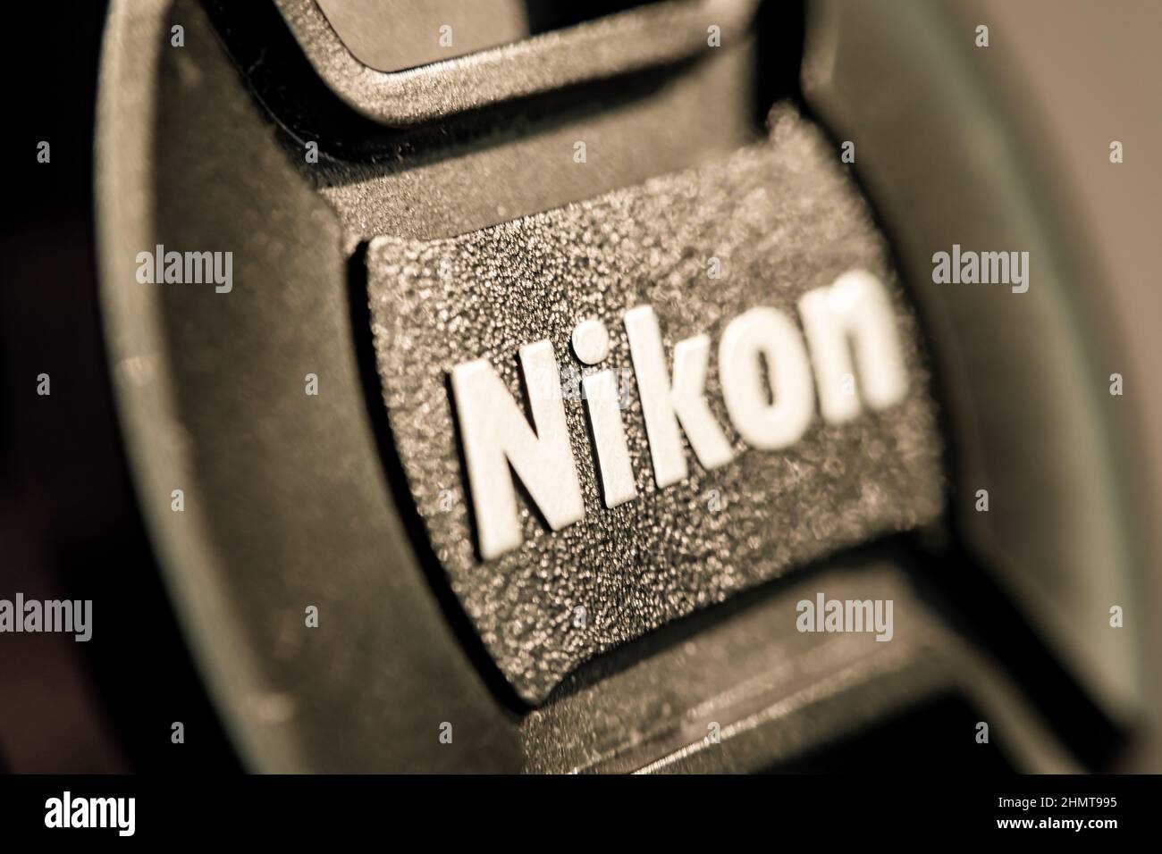 Nikon Frontlenabdeckung. Vorlauf und Rücklauf verschwommen. Konzentrieren Sie sich auf den i-Brief. Die Textur der Kunststoffoberfläche, die als Sonnenlicht dargestellt wird, wird reflektiert. Stockfoto