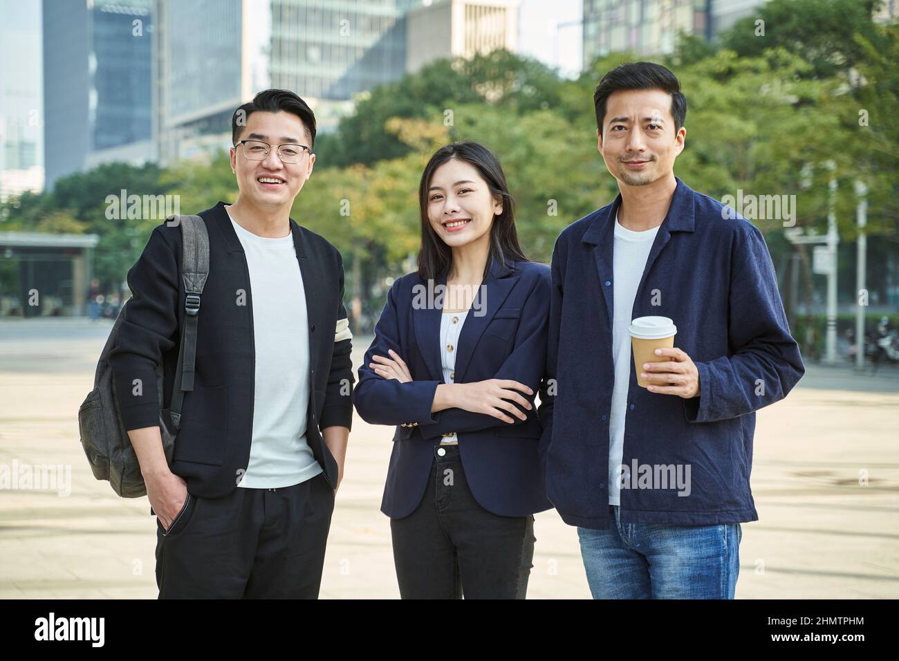 Außenportrait von drei jungen asiatischen Menschen, die glücklich und lächelnd stehen Stockfoto