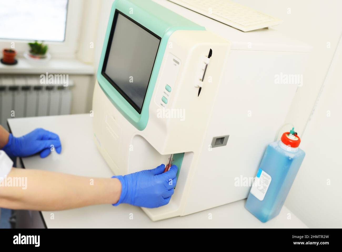 Ein Laborant untersucht eine Blutprobe in einem Analysator in einer modernen mikrobiologischen Klinik. Stockfoto
