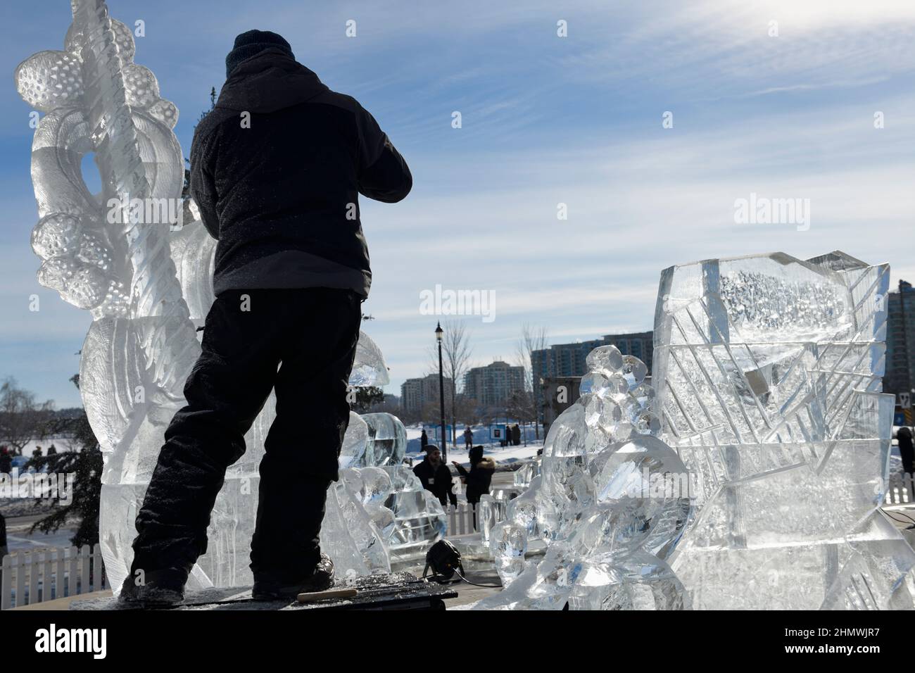 Mann, der beim Winterfest 2022 am Meridian Place in Barrie an der Eisskulptur eines Narwals arbeitet, heißt Hello Winter Stockfoto