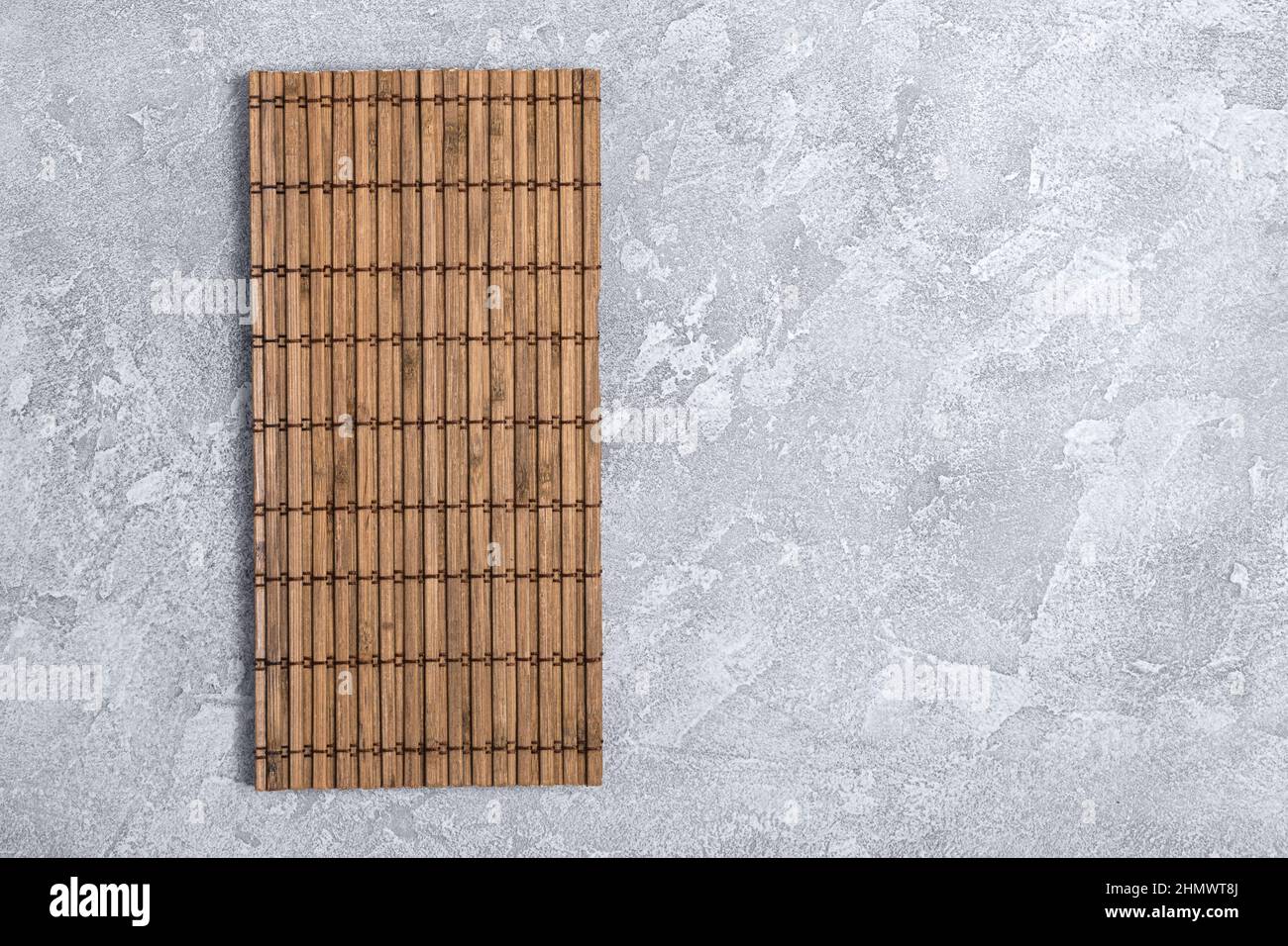 Draufsicht auf Bambusmatte für japanische Sushi auf grauem Beton-Hintergrund mit Kopierraum Stockfoto