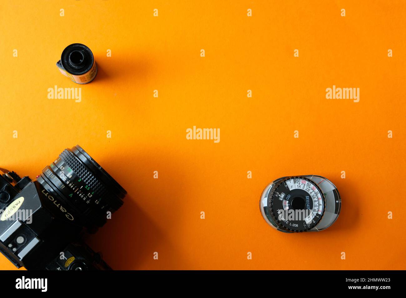 Lublin, Polen, 01. Februar 2022. Klassische Canon A1-Filmkamera, eine Rolle von Schwarz-Weiß-Film und analogem sekonic-Lichtmeter auf orangefarbenem Hintergrund - t Stockfoto