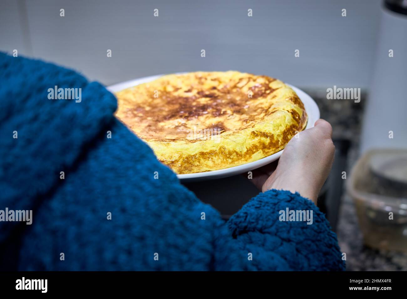Nicht erkennbare Frau, die ein spanisches Kartoffelomelett in der Hand hält. Stockfoto