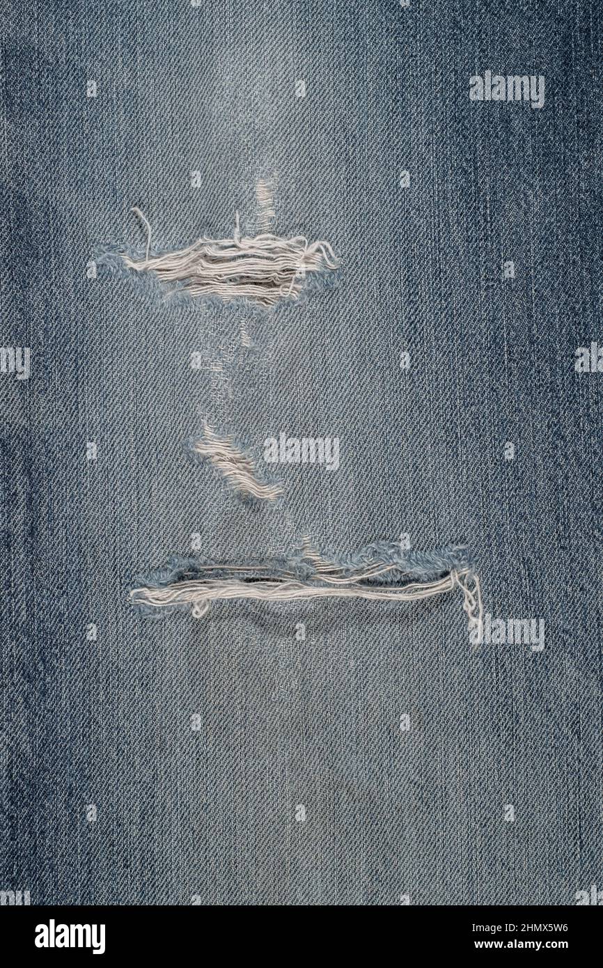 Detail der blauen Jeans Leinwand gerissen, mit Löchern, verzweifelt, verblasst und beschädigt für backgraund Stockfoto