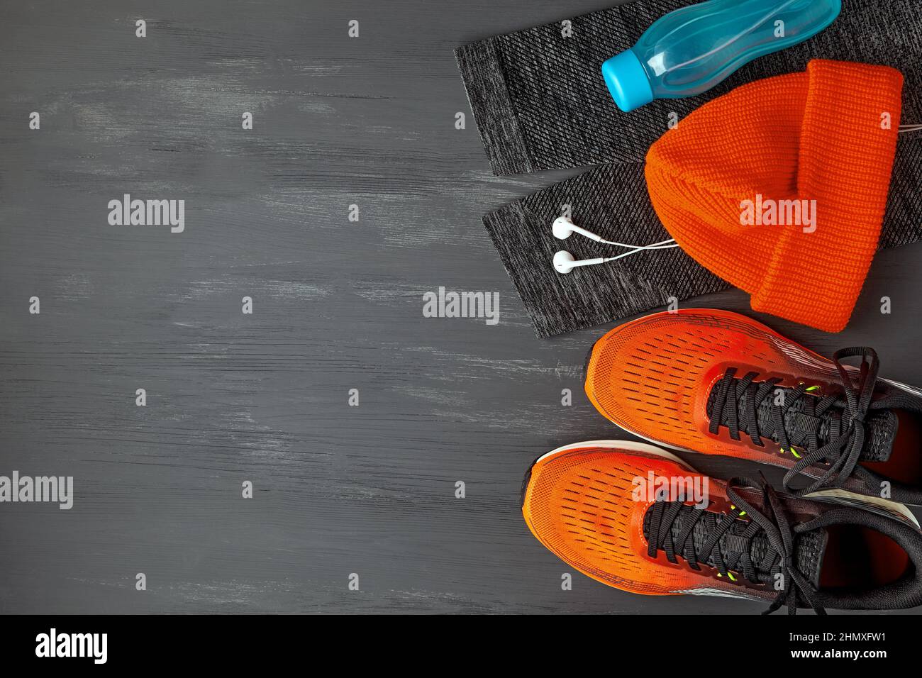 Orangefarbene warme Strickmütze, warme Sport-Leggings, Kopfhörer, Wasserflasche und orangefarbene Sneakers Stockfoto