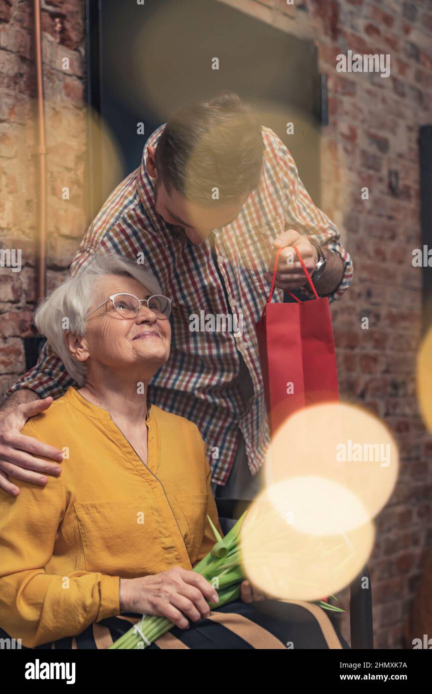 Enge Beziehung zwischen grauhaariger, pensionierter Großmutter, die am Tag der Großeltern ein Geschenk von ihrem ältesten Enkelkind erhalten hat. Hochwertige Fotos Stockfoto