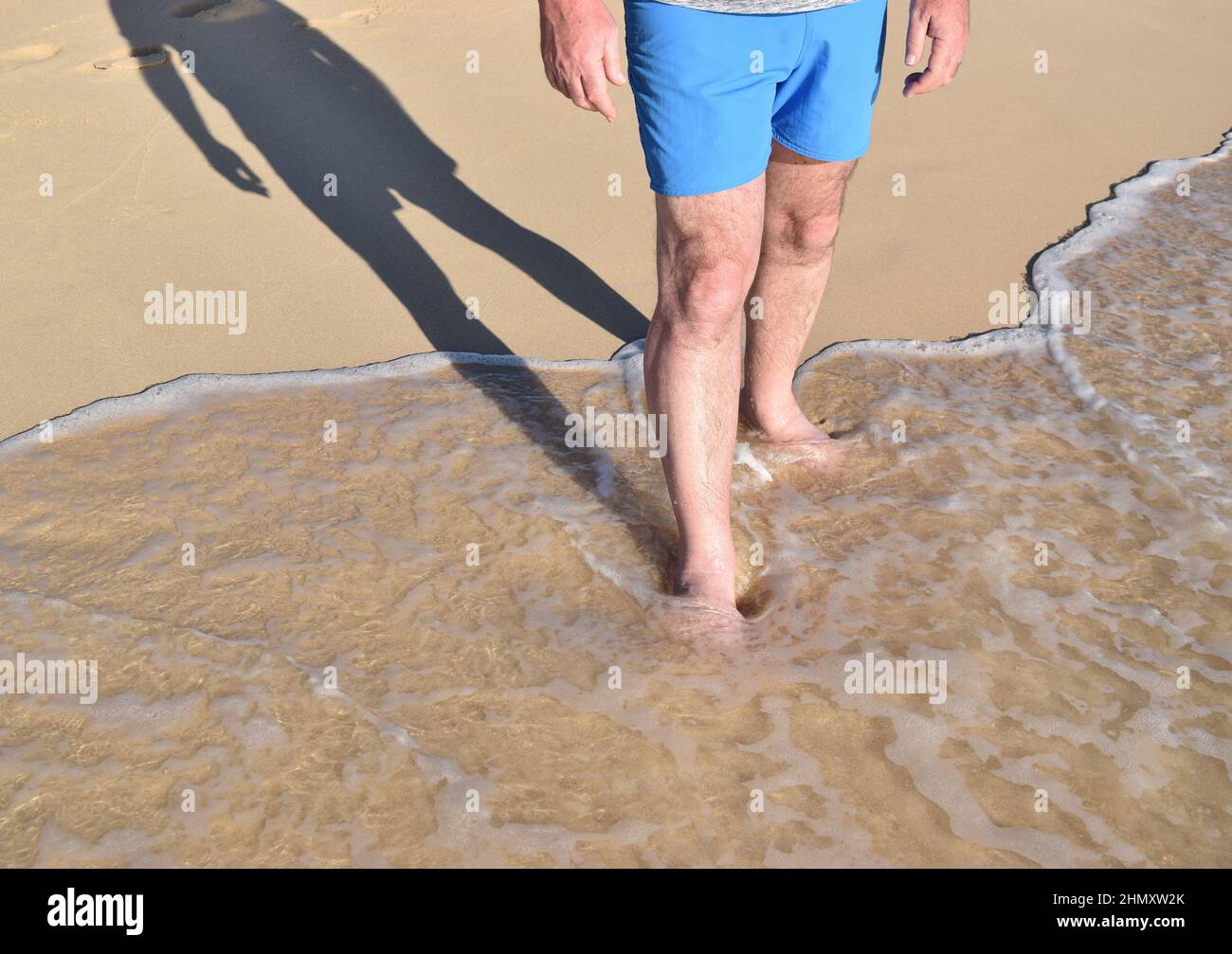 Mann, der auf Barbados an einem sonnenbeschienenen Sandstrand steht. Stockfoto