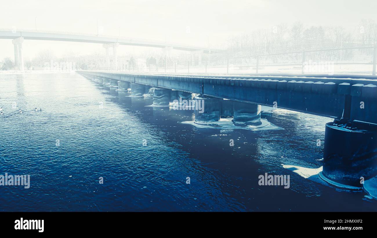 Um die Säulen der Eisenbahnbrücke bildet sich Eis mit einer dünnen Nebelschicht Stockfoto
