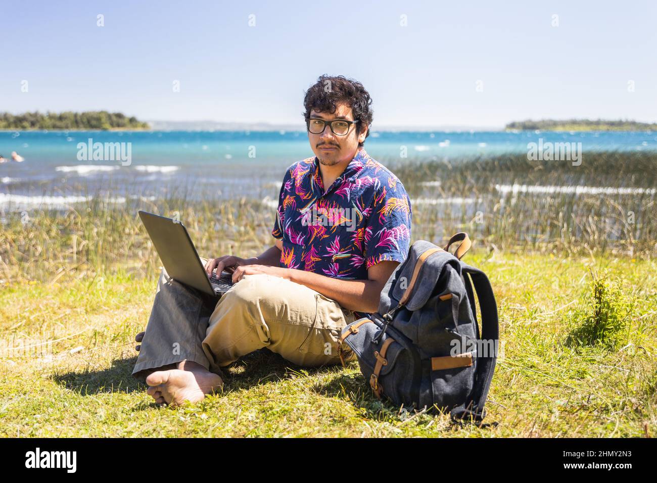 Junger lateiner, der am Strand Remote online arbeitet. Telearbeitskonzept. Stockfoto