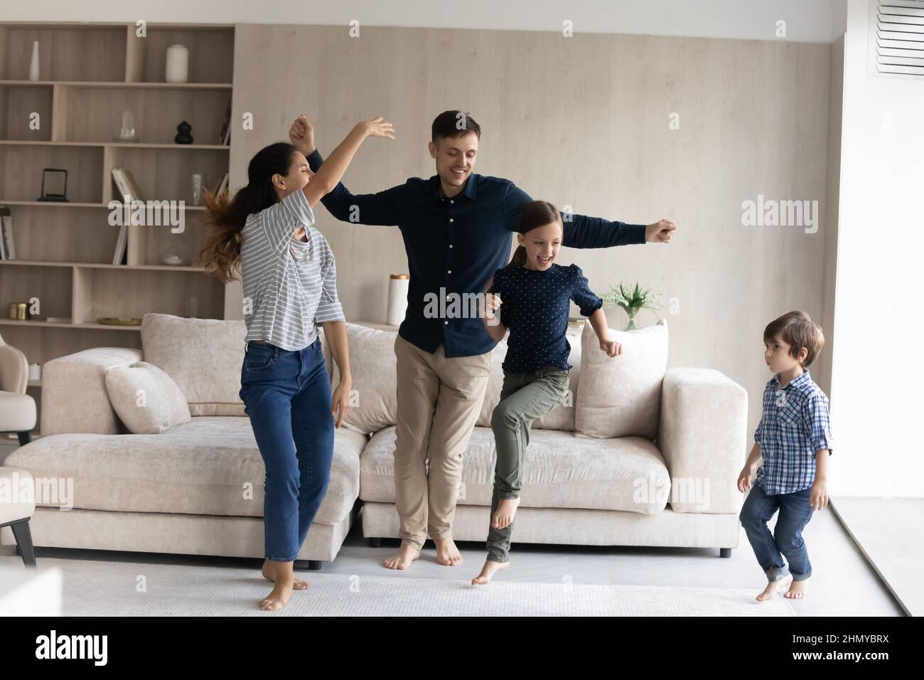Fröhliche Familie von neuen Hausbesitzern, die im Wohnzimmer tanzen Stockfoto