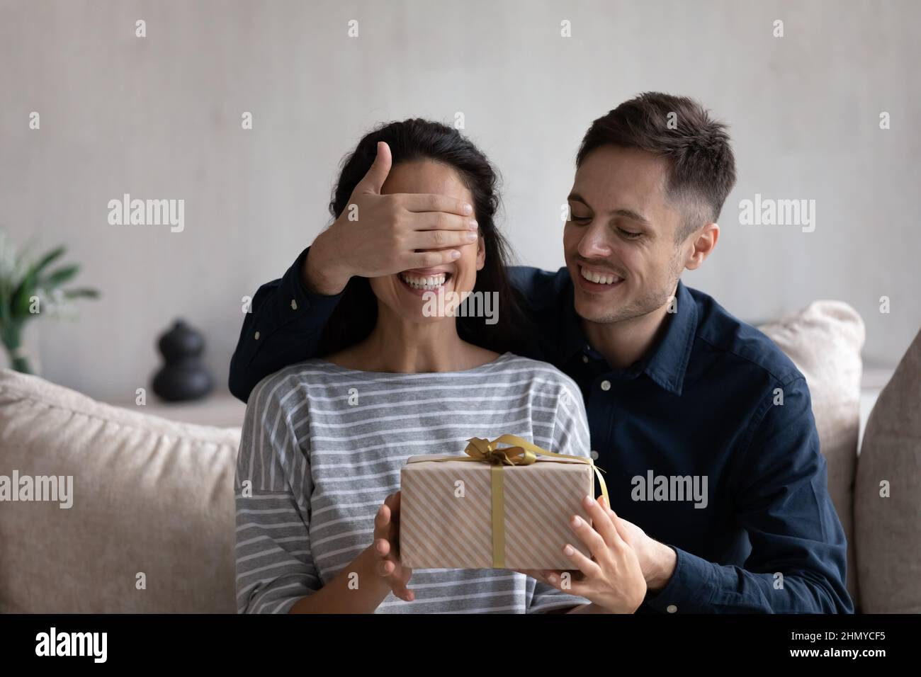 Glücklicher Ehemann, der der aufgeregten Frau ein Überraschungsgeschenk gab Stockfoto