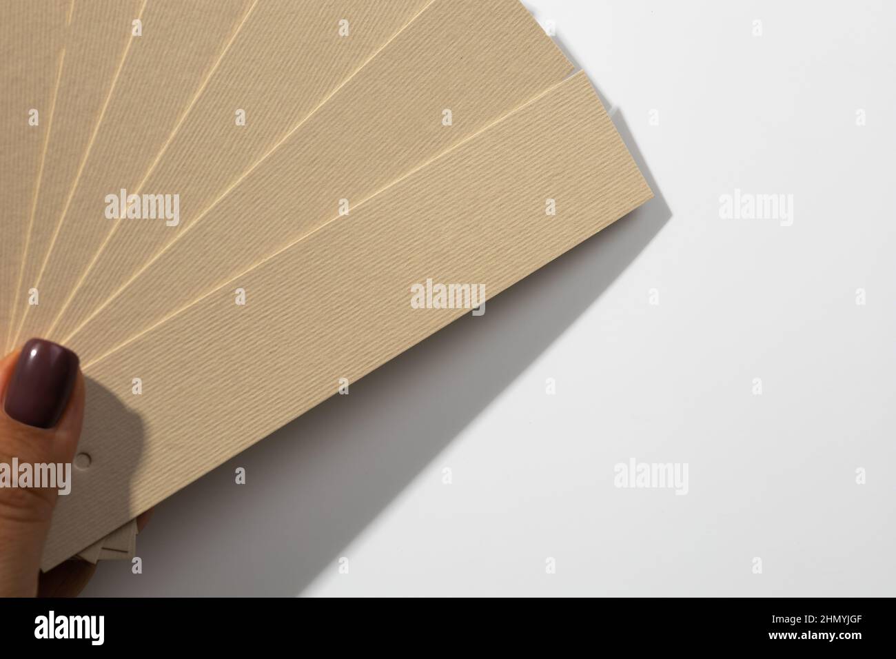 Nahaufnahme von leeren rechteckigen Kartons aus Pappe mit winzigen Löchern im unteren Teil, die wie ein Fächer in der Frauenhand angeordnet sind und Schatten auf weißen Hintergrund fallen Stockfoto