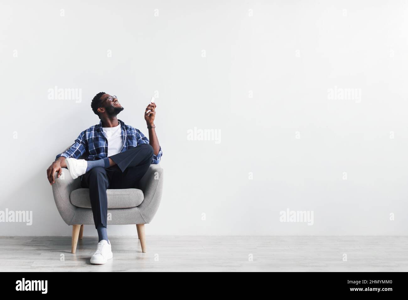 Geteiltes System. Junger schwarzer Mann mit Fernbedienung, der die