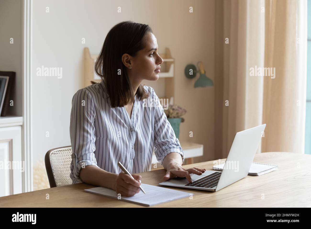 Abgelenkt von Computerarbeit nachdenkliche junge Geschäftsfrau, die in der Ferne schaut. Stockfoto
