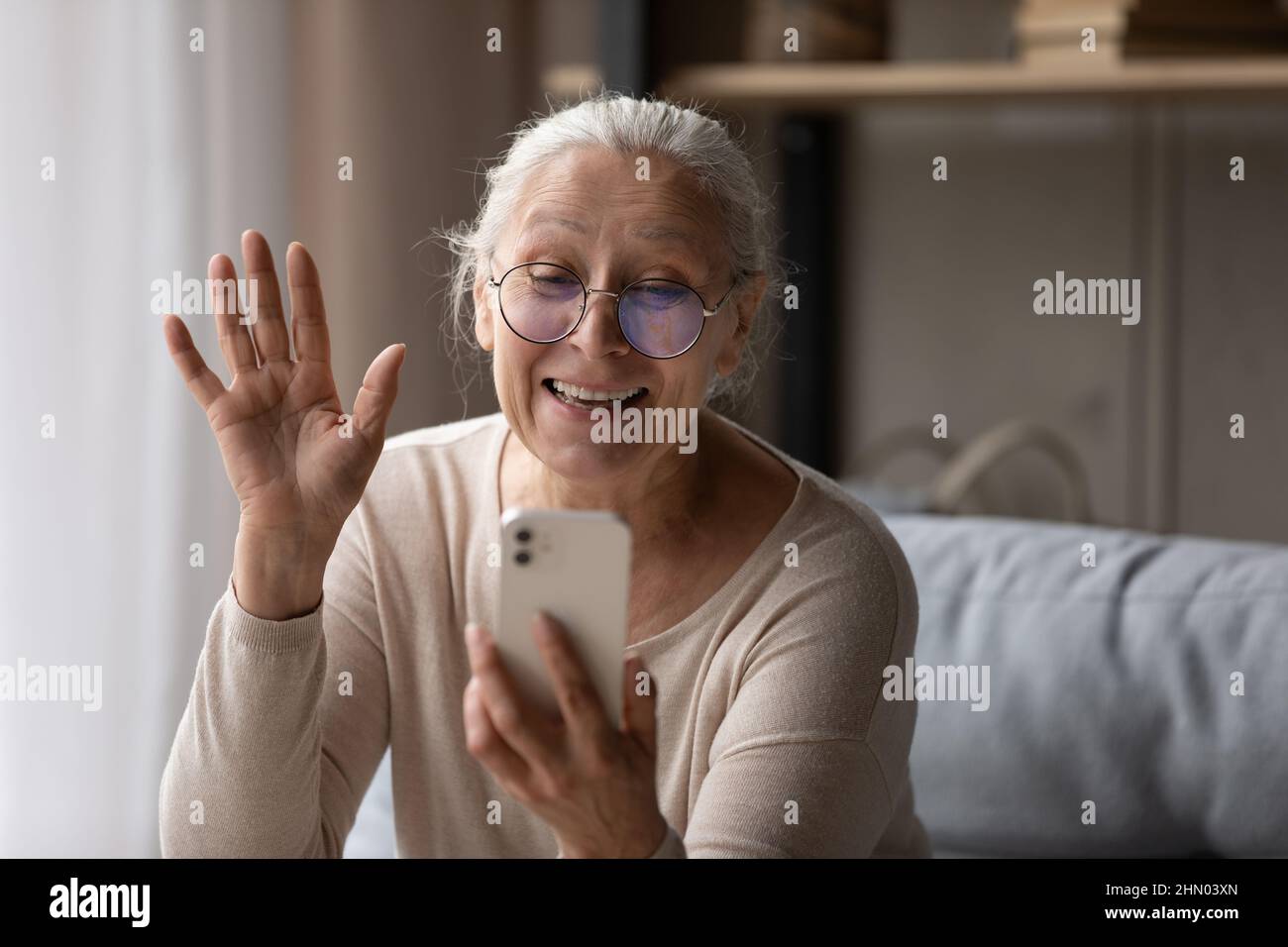 Glückliche ältere Smartphone-Nutzer Frau winkt Hand Hallo auf dem Bildschirm Stockfoto