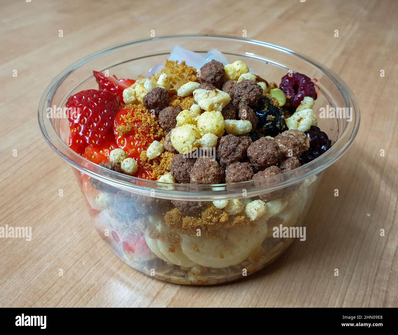 Griechischer Joghurt mit frischem Obst, Nüssen, Müsli und Müsli. Nehmen Sie das Dessert in einer Plastikschüssel mit. Stockfoto