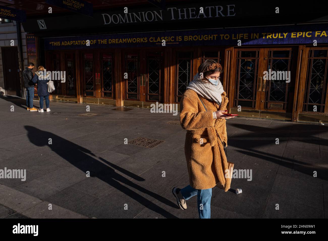 Eine Frau geht an einem hellen, aber kühlen Wintermorgen am Dominion Theatre im Londoner West End vorbei. London, Großbritannien Stockfoto