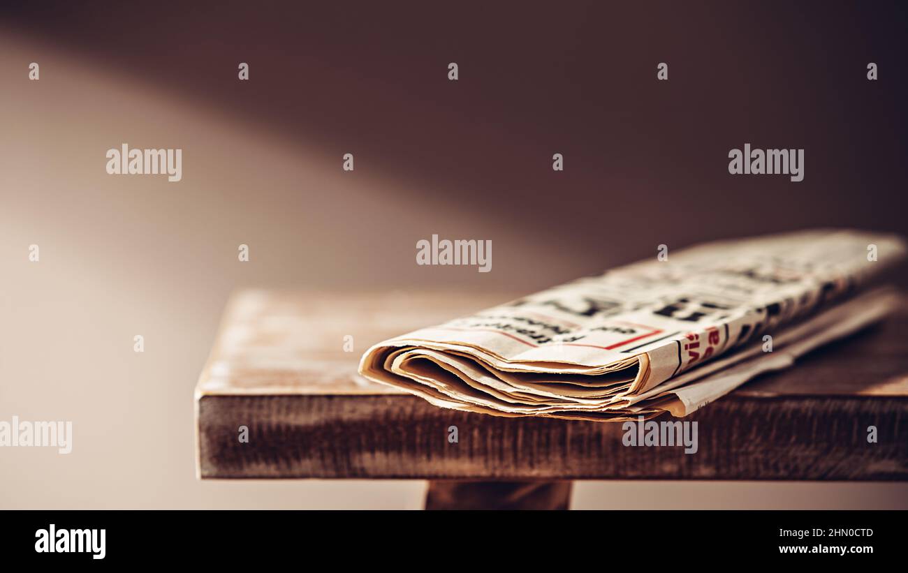Gute alte Zeitung auf einer Holzbank im Licht einer Stehleuchte Stockfoto
