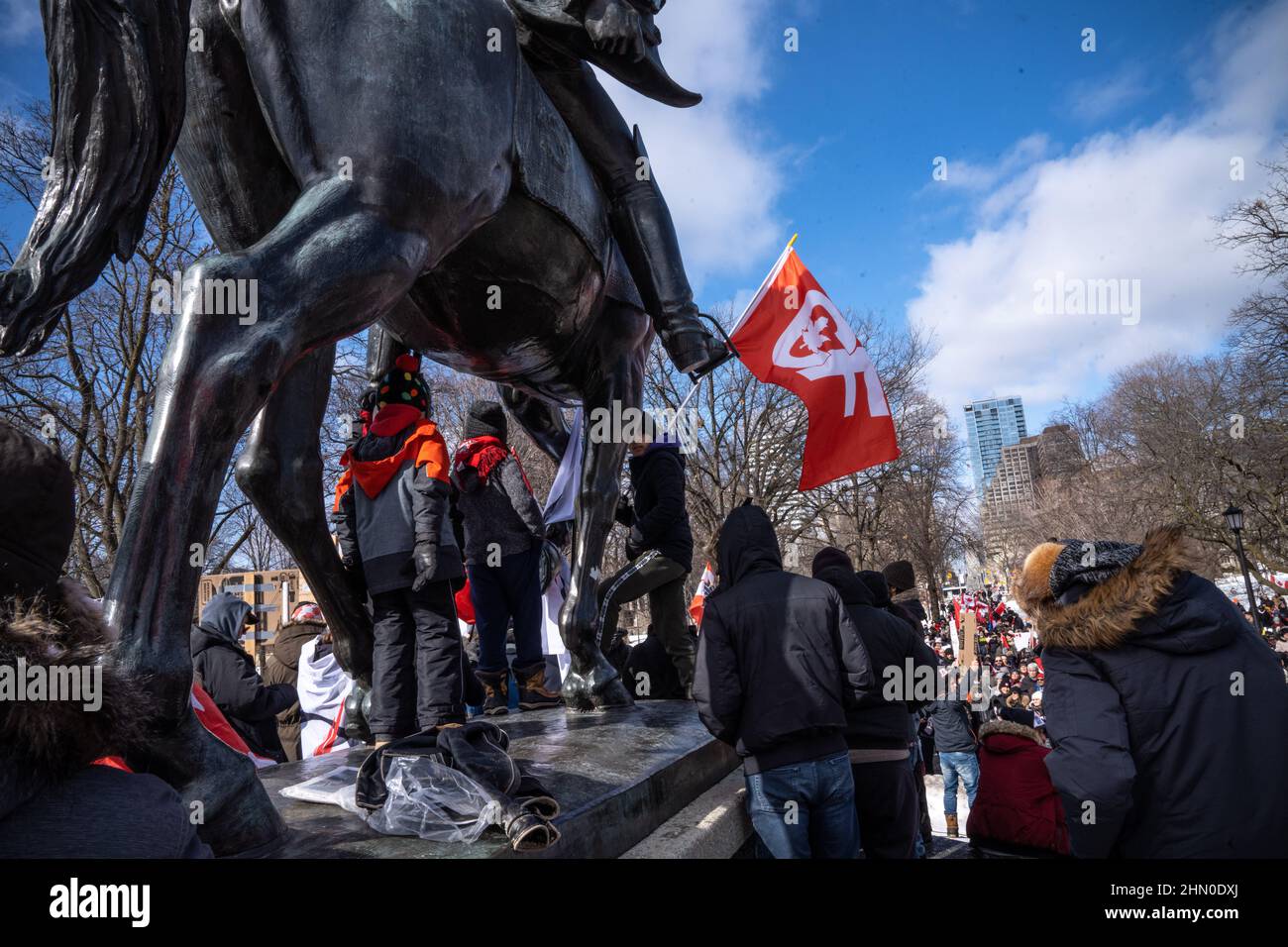 Toronto, Kanada. 12th. Februar 2022. Demonstranten versammeln sich um ein Denkmal, um während einer Kundgebung mit einer Menschenmenge zu sprechen.Trucker Konvoi Demonstranten versammeln sich am zweiten Wochenende in Folge im Queen's Park, Toronto, um sich solidarisch mit Anti-Mandats-Demonstrationen zu zeigen. Er kommt, nachdem die Provinz den Ausnahmezustand in Bezug auf die anhaltenden Blockaden erklärt hat, und die Polizei von Toronto Straßensperrungen in der ganzen Stadt eingerichtet hat. (Foto von Katherine Cheng/SOPA Images/Sipa USA) Quelle: SIPA USA/Alamy Live News Stockfoto