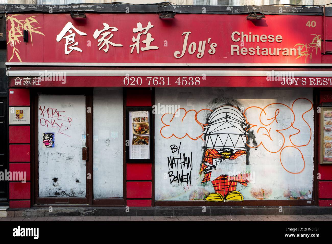 Dieses Bild zeigt ein chinesisches Restaurant, das entweder dauerhaft oder wegen Bauarbeiten geschlossen ist. Das Fenster zeigt Kunstwerke des Straßenkünstlers Nathan Bowen Stockfoto