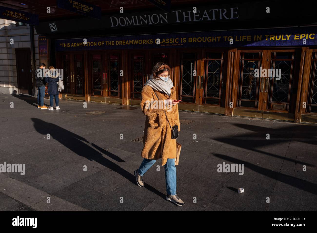 Eine Frau geht an einem hellen, aber kühlen Wintermorgen am Dominion Theatre im Londoner West End vorbei. London, Großbritannien Stockfoto