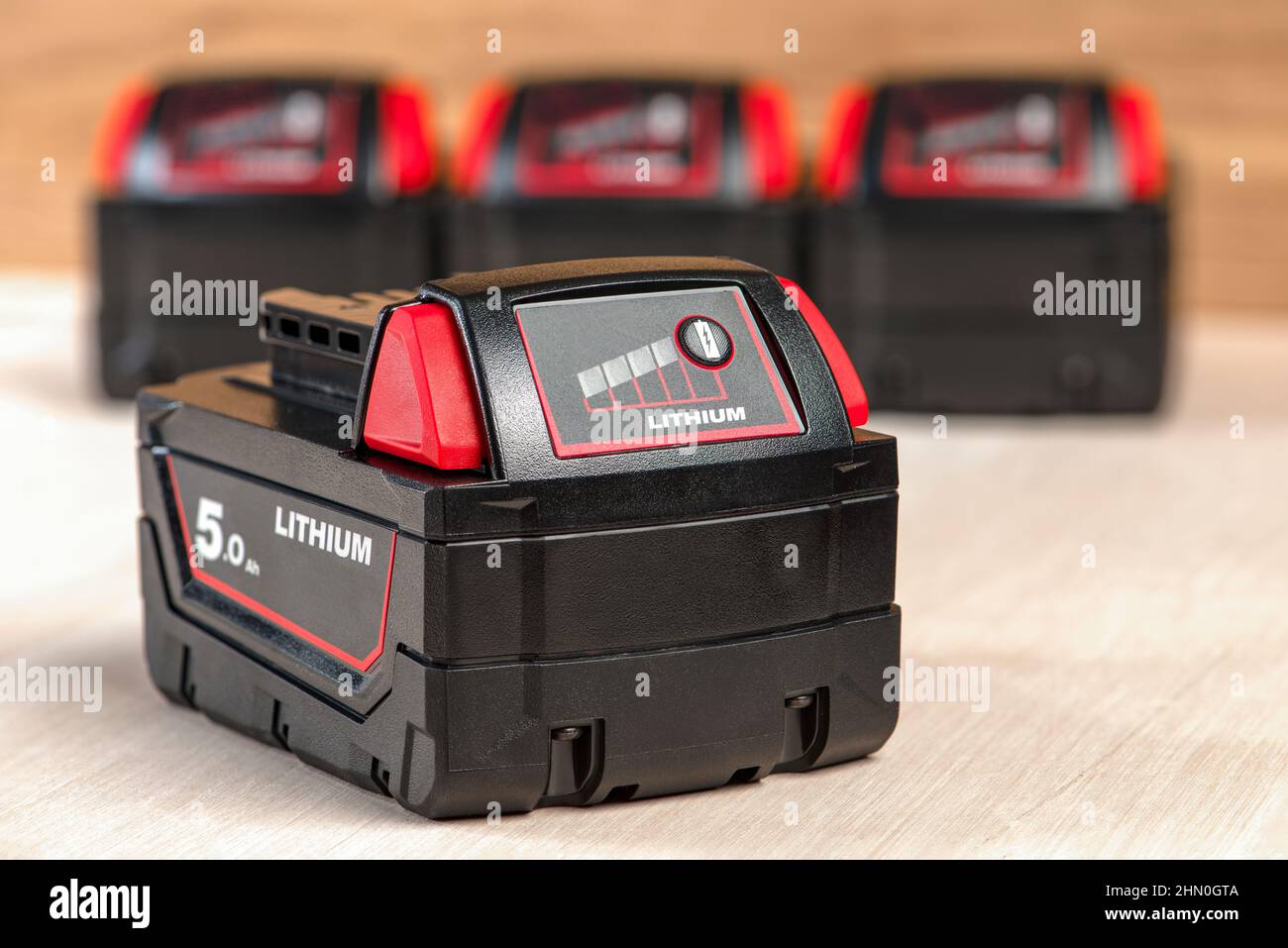 Akku für Akku-Bohrmaschine. Schrauberbatterie. Vier Batterien mit Ladeanzeige liegen auf einem Holzhintergrund Stockfoto