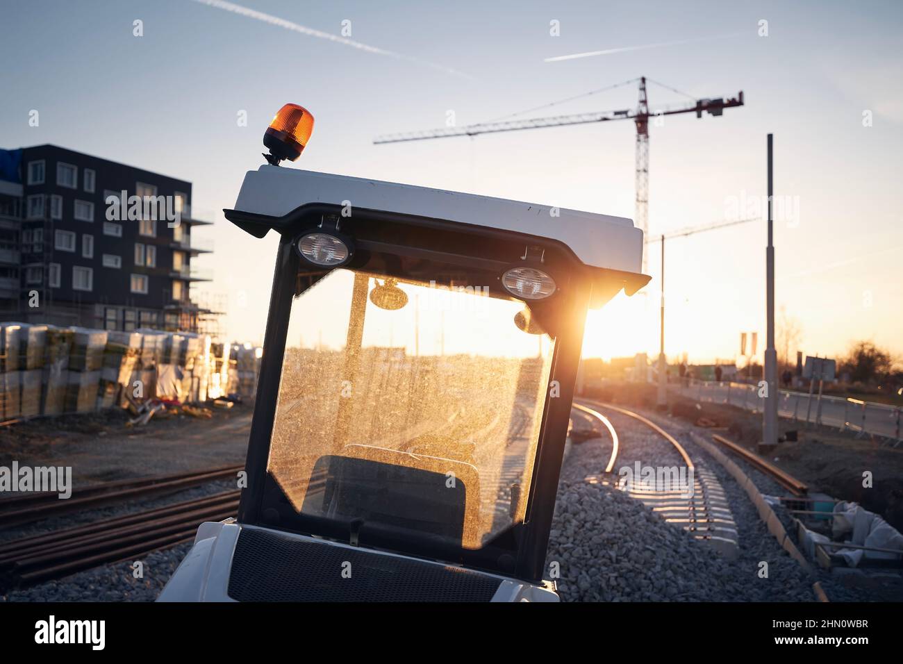 Maschinen auf der Baustelle der Eisenbahnstrecke bei Sonnenuntergang. Bau einer neuen Straßenbahnverbindung in der Stadt. Stockfoto
