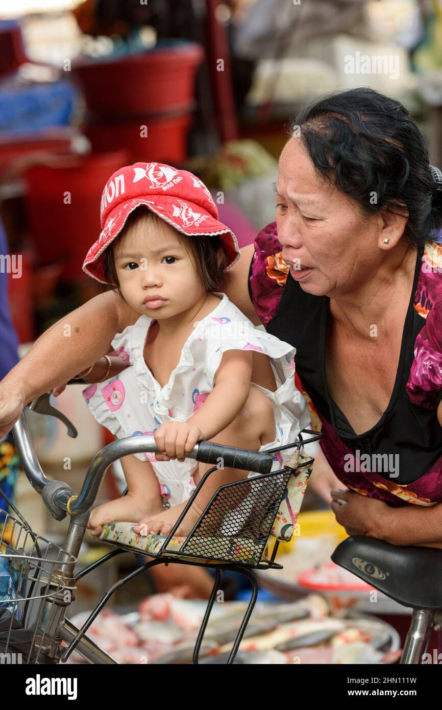 Ein junges vietnamesisches Mädchen sitzt auf einem Fahrrad auf dem geschäftigen Lebensmittelmarkt am Morgen in Cai Rang, in der Nähe von Can Tho, Mekong Delta, Südvietnam Stockfoto