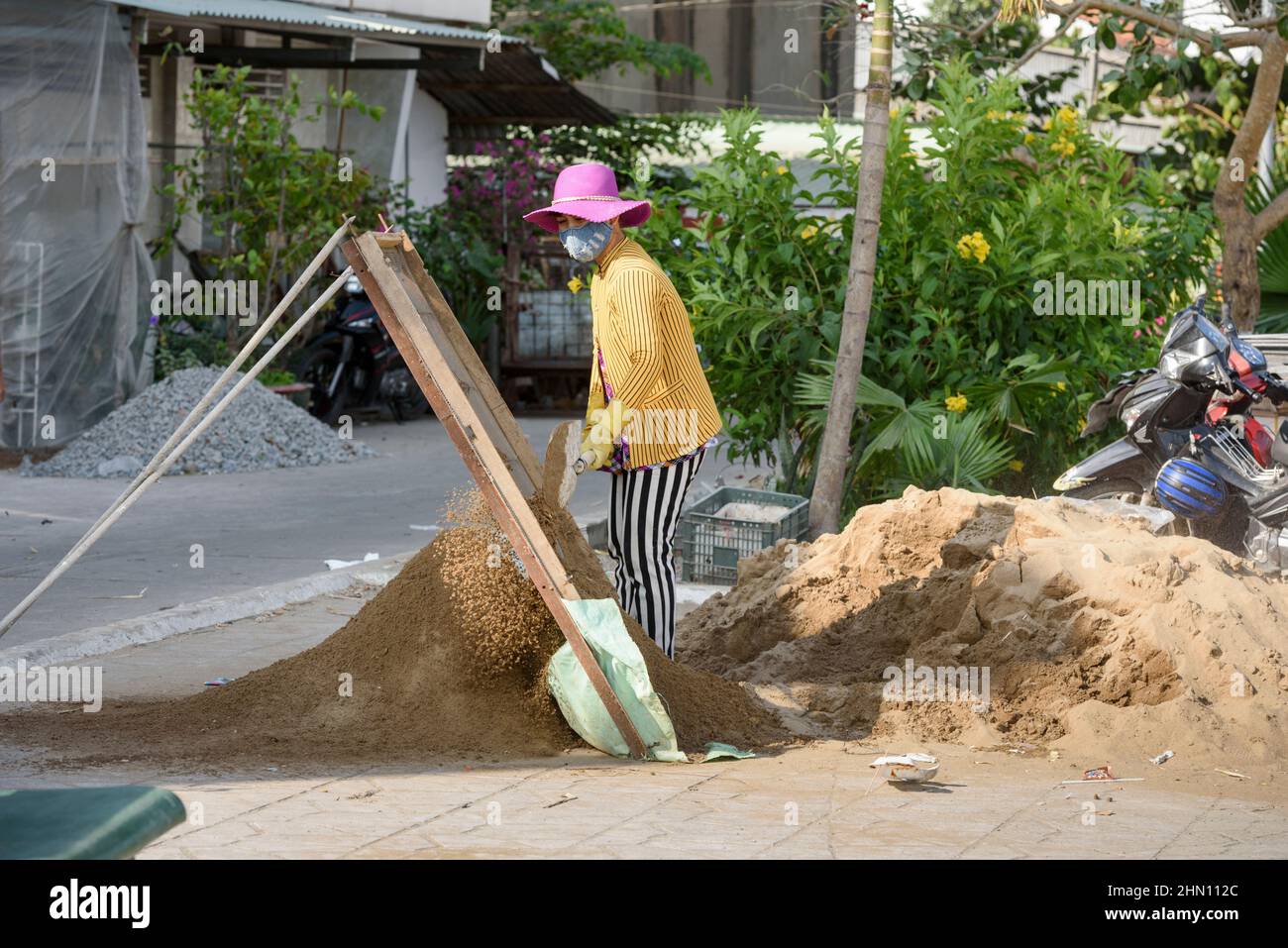 Eine junge Arbeiterin siebt Boden mit einem großen Sieb am Straßenrand in Cai Rang, nahe Can Tho, Mekong Delta, Südvietnam, Südostasien Stockfoto