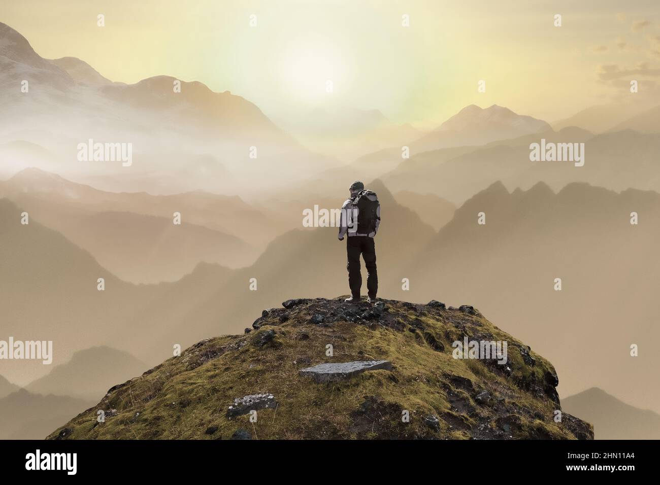 Ein einsamer Mann auf dem Gipfel des Berges steht mit seinem Rücken und blickt auf den Sonnenuntergang. Hochwertige Fotos Stockfoto