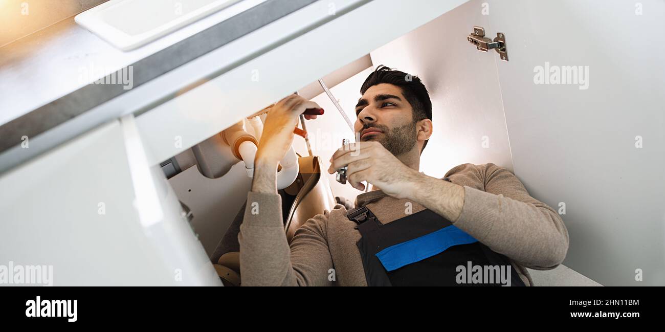 Klempner repariert Spülbecken in der Küche Stockfoto