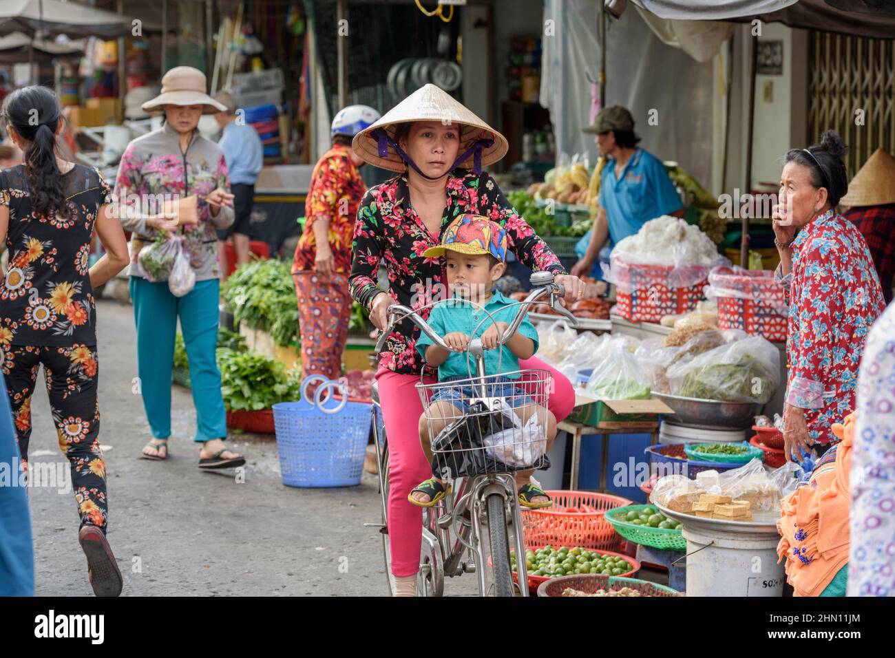 Eine Vietnamesin radelt mit ihrem Sohn durch den belebten Lebensmittelmarkt in Cai Rang, in der Nähe von Can Tho, Mekong Delta, Südvietnam Stockfoto