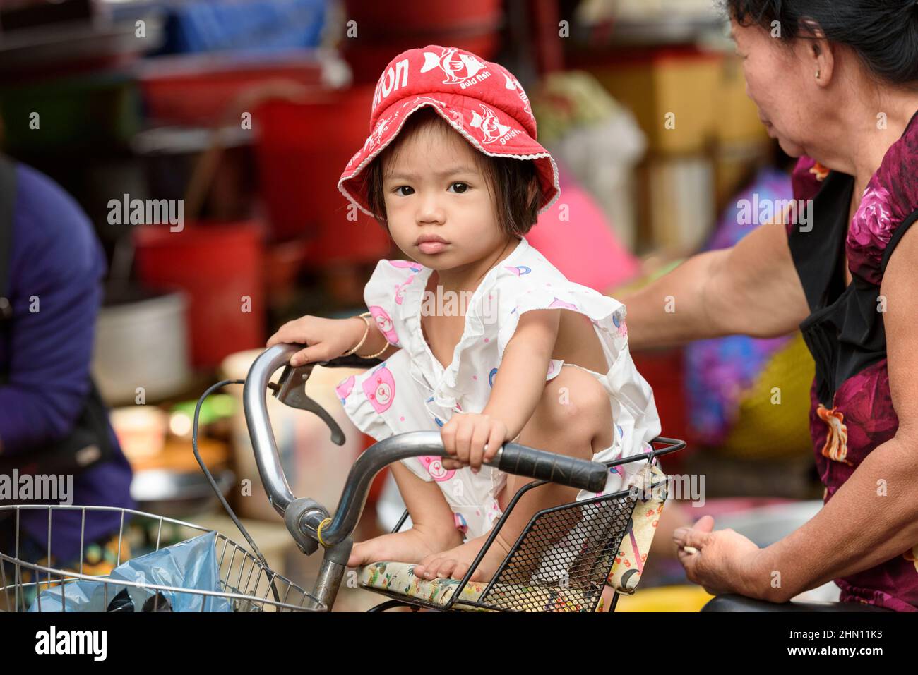 Ein junges vietnamesisches Mädchen sitzt auf einem Fahrrad auf dem geschäftigen Lebensmittelmarkt am Morgen in Cai Rang, in der Nähe von Can Tho, Mekong Delta, Südvietnam Stockfoto