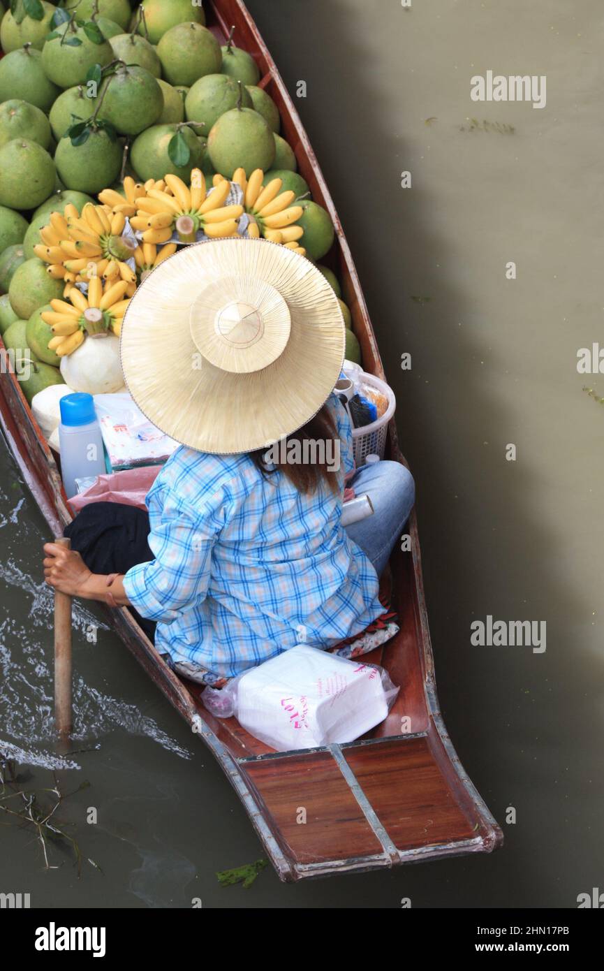 Thailand Sep 9th 2008 Schwimmender Markt. Thailänderin paddelt in einem Boot, das mit grünen Kokosnüssen und Bananen beladen ist. Luftaufnahme. Stockfoto