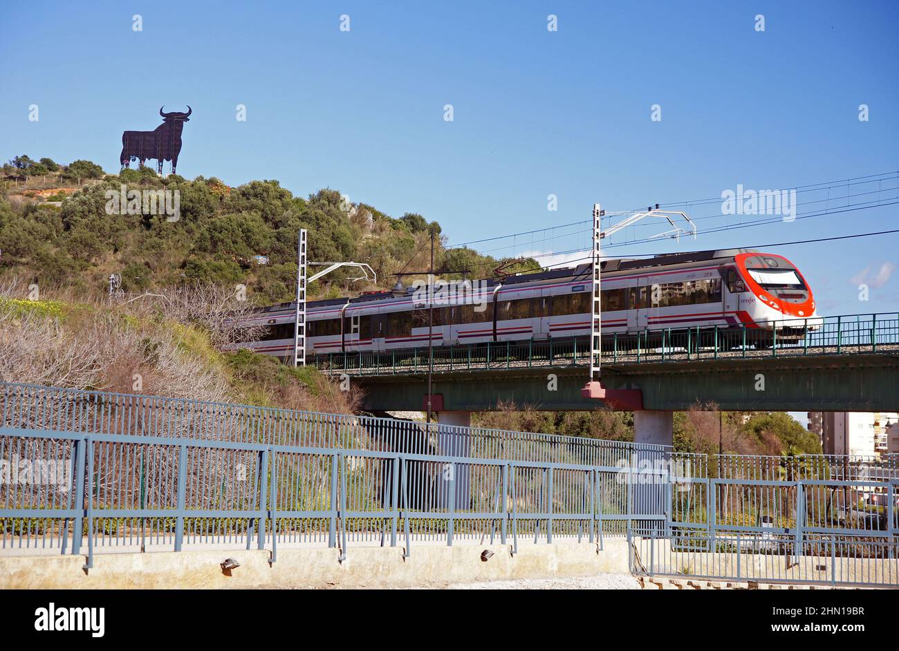 Andalusien in Spanien: Die Eisenbahnlinie in der Nähe der Stadt Fuengirola. Man beachte den Osborne-Stier (Toro d'Osborne) am Horizont Stockfoto