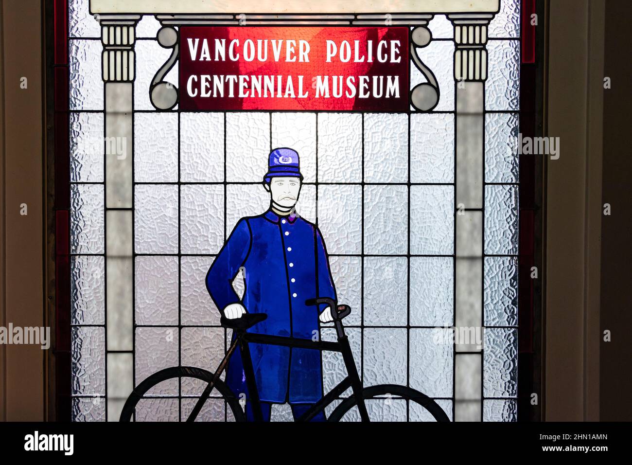 Buntglasfenster mit einem viktorianischen Polizisten und einem Fahrrad im Polizeimuseum von Vancouver Stockfoto