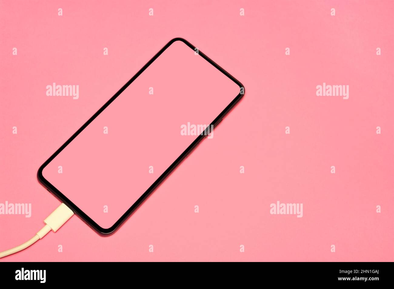 Handy-Ladevorgang auf rosa Hintergrund. Konzeptionell. Stockfoto