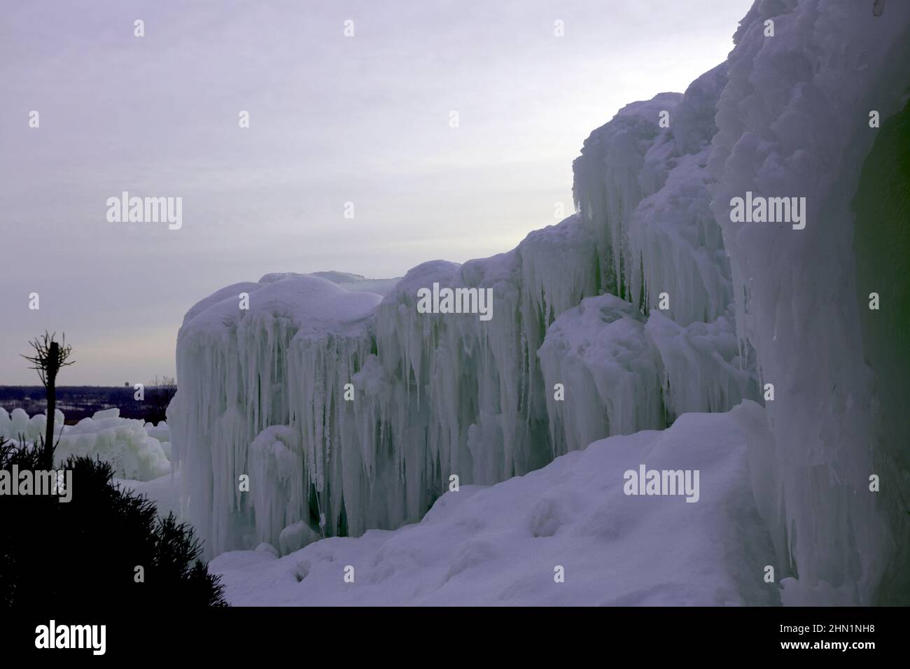 Eine Wand aus gefrorenen Eisblöcken und Eiszapfen gegen den Himmel bei Ice Castles im Genfersee, Wisconsin, USA Stockfoto