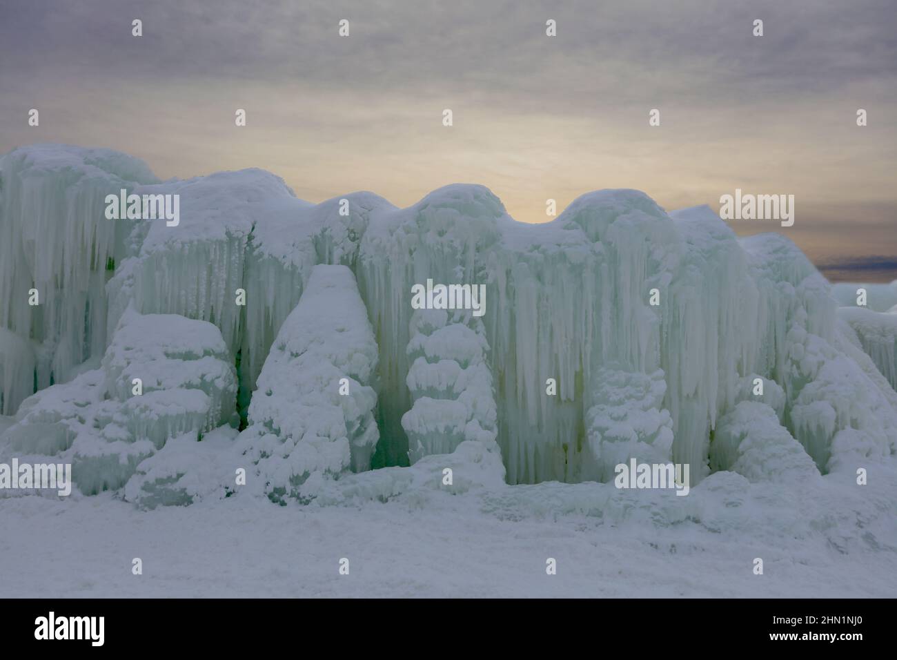 Eine Wand aus gefrorenem Wasser und Eiszapfen stand im Kontrast zum Sonnenuntergang an den Eisschlössern im Genfersee, Wisconsin, USA Stockfoto