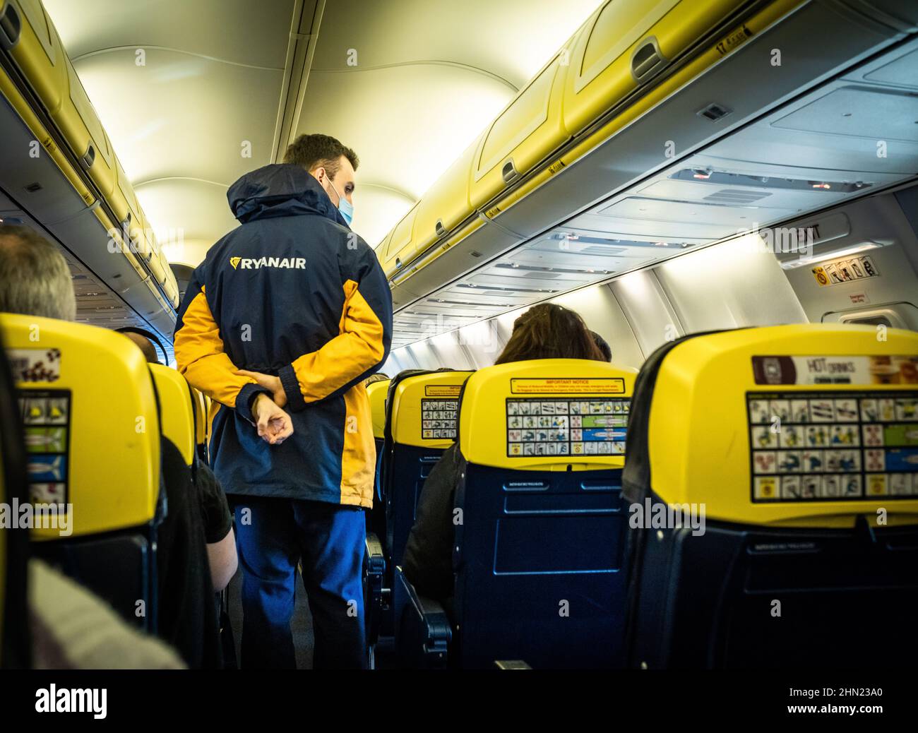 Ein männlicher Ryanair-Flugbegleiter überprüft Passagiere in einer Boeing 737 kurz vor dem Abflug. Dies ist der Flug FR121 von London Gatwick nach Dublin. Stockfoto