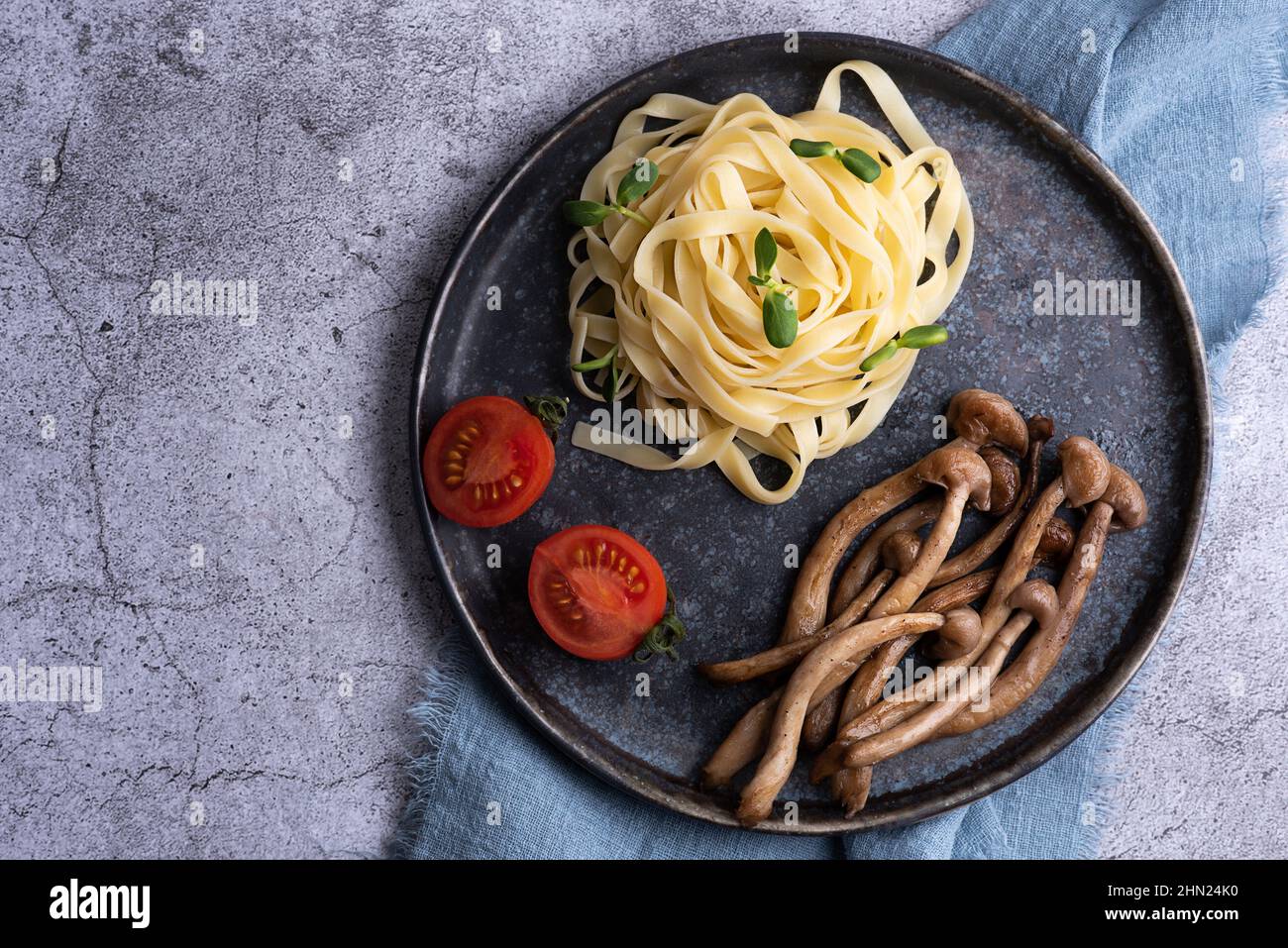 Gebratene Shimeji serviert mit Nudeln auf dem Teller, Pilze und Pasta auf grauem Hintergrund. Stockfoto