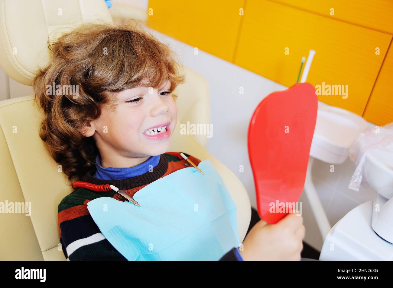 Ein kleiner Junge mit lockigen Haaren in einem Zahnarztstuhl Stockfoto