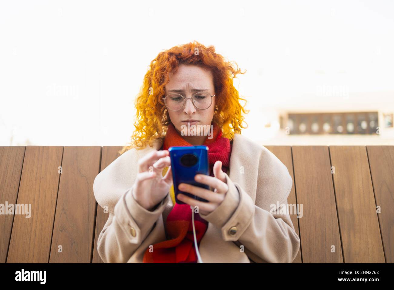 Besorgte junge Frau beim Lesen der Nachrichten auf ihrem Smartphone Stockfoto