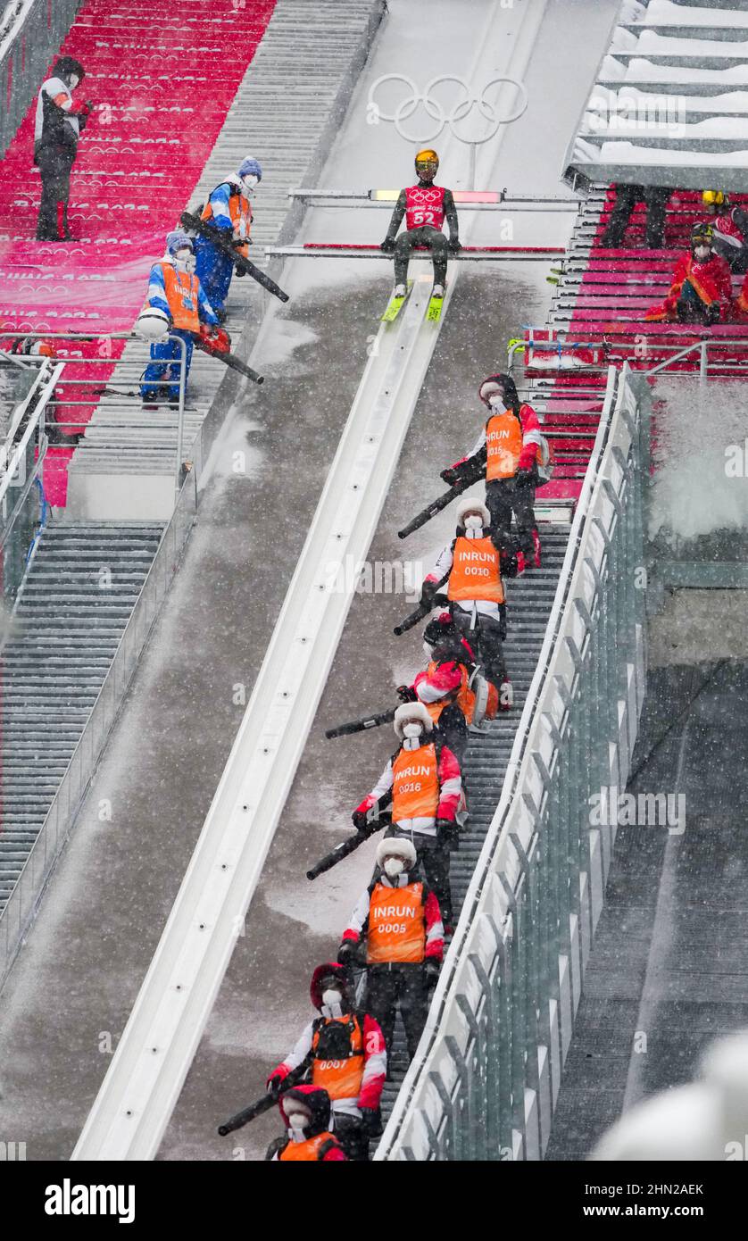 Zhangjiakou, Chinas Provinz Hebei. 13th. Februar 2022. Freiwillige säubern den Schnee während des offiziellen Trainings der nordischen Kombination gundersen Large Hill/10km im Nationalen Skisprungzentrum in Zhangjiakou, nordchinesische Provinz Hebei, 13. Februar 2022. Quelle: Zhu Zheng/Xinhua/Alamy Live News Stockfoto