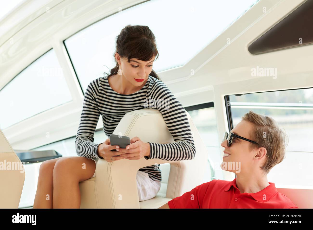 Eine junge Frau schreibt Freunden SMS und spricht mit ihrem Freund, wenn sie die Yacht genießen Stockfoto